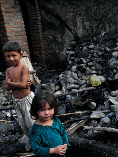 Two children standing next to home destroyed by a U.S. drone