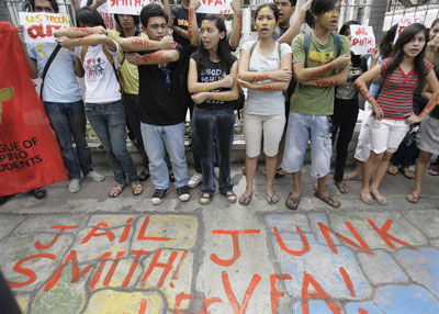 A protest in the Philippines in  2009 after the rape of a Filipina woman by a U.S. Marine. The U.S. refused to turn the rapist over to Philippine courts citing the "Visiting Forces Agreement" (VFA) which provides immunity for U.S. military personnel accused of committing rape. On the protester's arms and on the ground is written "Jail Smith" (the Marine rapist) and "Junk VFA."