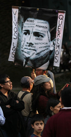 A protester holds a defaced image of Mexico's President Enrique Pena Nieto that reads in Spanish 'We want them alive' in Mexico City,, December. 6. Photo: AP