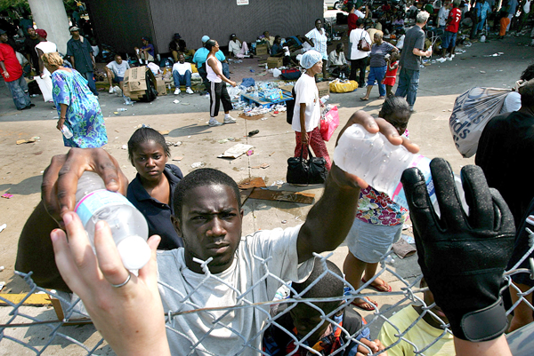 Bottles of water are handed over a fence to Hurricane Katrina victims at a temporary hospital set up at the New Orleans airport, September 3, 2005.