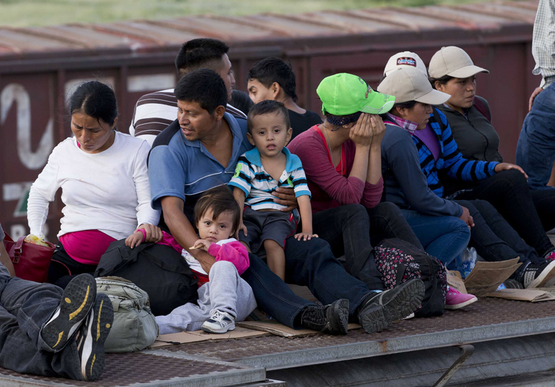 Central American families, including young children, riding on top of a freight train through Mexico on the way to the U.S. border, July 2014.