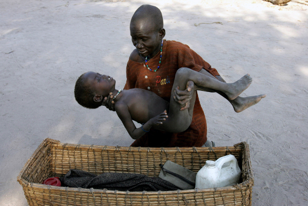 A mother takes her son to a Medecins Sans Frontieres clinic to be treated for malaria, Lankien, Southern Sudan, 2005.