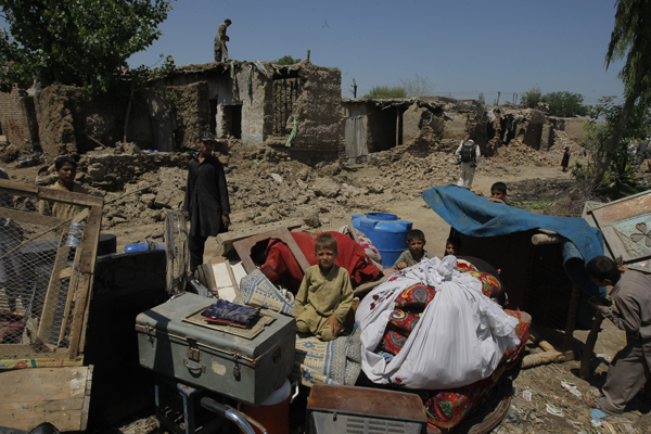 A family of Afghan refugees who fled war in their homeland collect their belongings in Peshawar, Pakistan as refugee homes are demolished by government authorities. Many refugees face deportation back to Afghanistan.