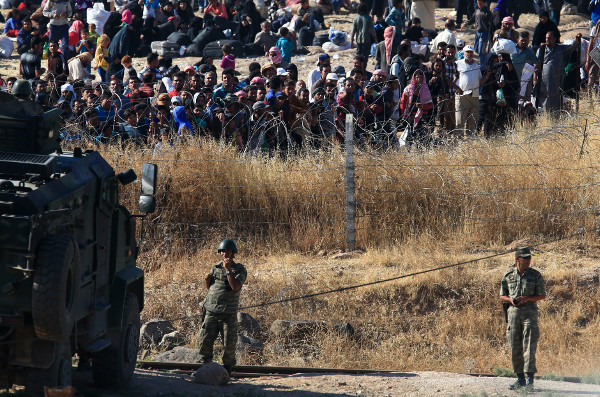 Turkish soldiers guard border as Syrian refugees wait on the Syrian side to cross, June 2015.