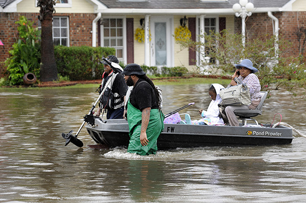 Volunteers pull a boat with a woman and young child as they evacuate from their homes, Aug. 13, 2016, in Baton Rouge