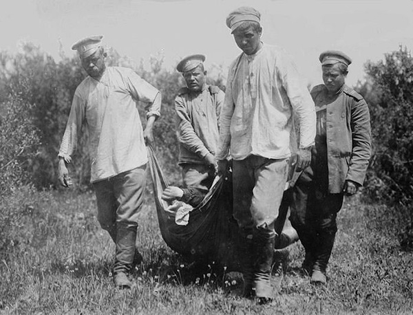 Four men drag a body across a field.