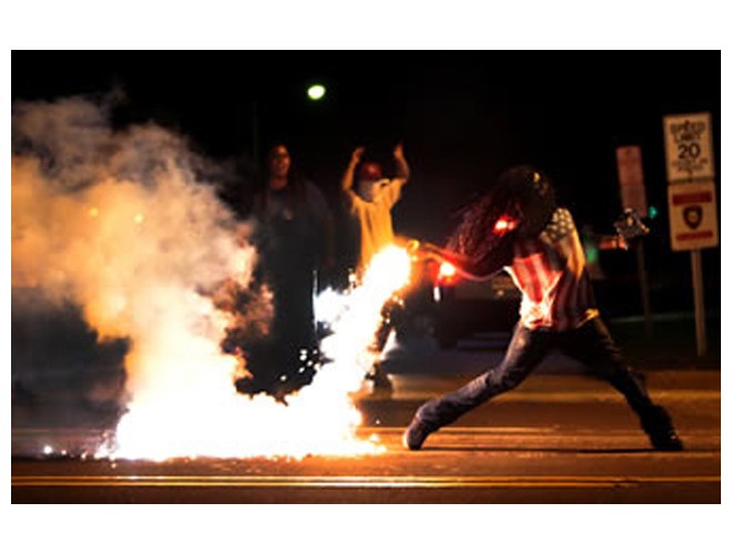 Manifestante devuelve casco de gas lacrimógeno que policías lanzaron al pueblo, Ferguson, 13 agosto. Foto: AP 